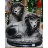 A PAIR OF STAFFORDSHIRE LIONS IN BLACK AND WHITE WITH GLASS EYES
