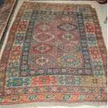 AN ANTIQUE CAUCASIAN KAZAK RUG, THE RECTANGULAR BLUE GROUND DECORATED WITH TEN RECTANGULAR PANELS