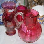 A MARY GREGORY STYLE CRANBERRY GLASS JUG, TOGETHER WITH ANOTHER CRANBERRY GLASS JUG, AND A CRANBERRY