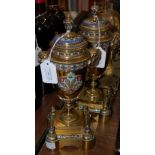 A PAIR OF LATE 19TH CENTURY BRASS AND CHAMPLEVE ENAMEL URNS ON INTEGRAL STANDS