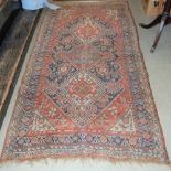 AN ANTIQUE PERSIAN RUG, THE RECTANGULAR MADDER GROUND CENTRED WITH THREE LOZENGE SHAPED MEDALLIONS