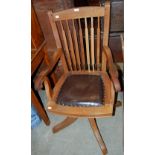 A DARK WOOD REVOLVING DESK CHAIR WITH BROWN LEATHERETTE UPHOLSTERED SEAT