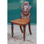 A Victorian mahogany hall chair, the scroll carved back centred with a vacant shield, the solid seat