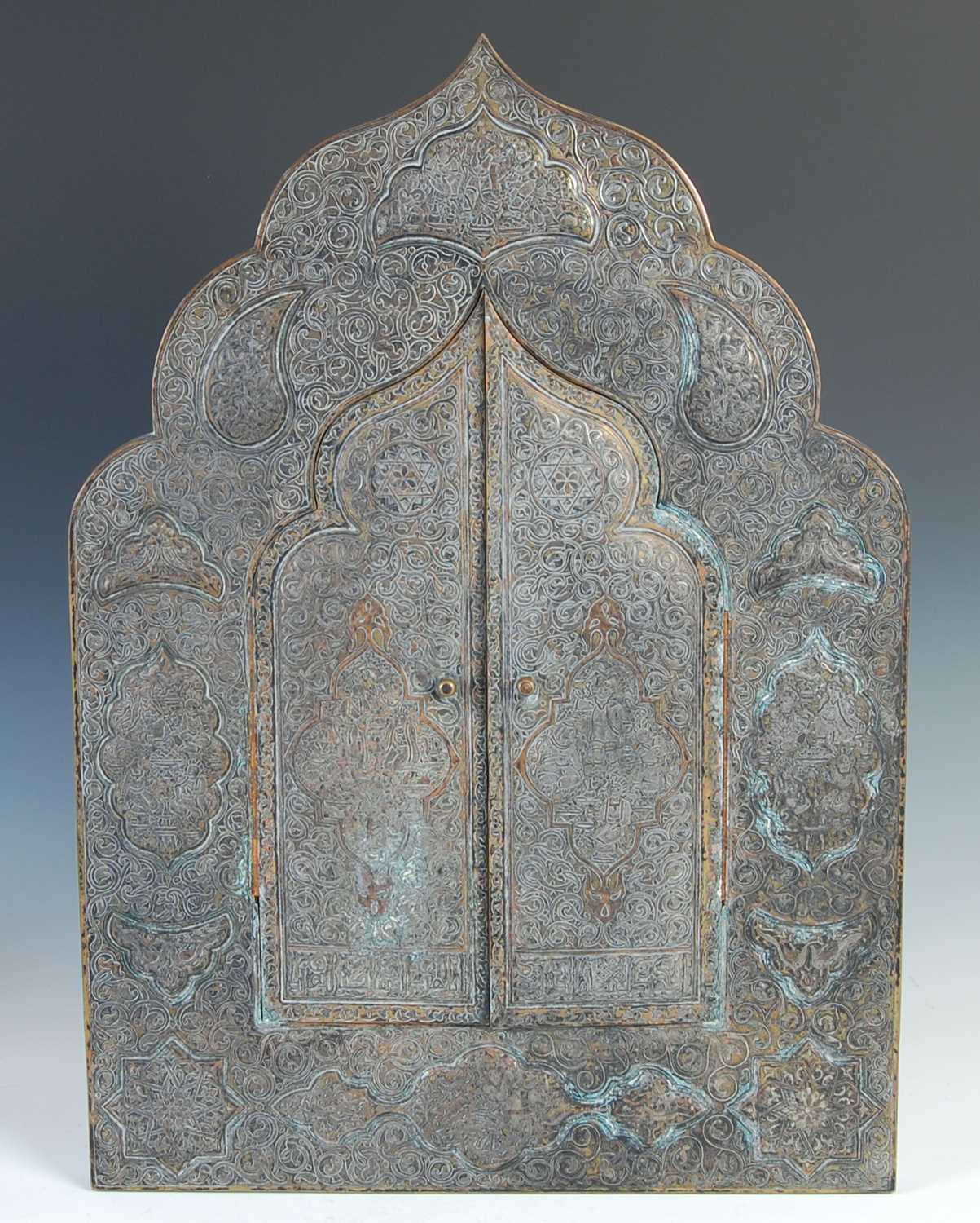 A 19th century Persian brass, copper and white metal inlaid mihrab shaped wall mirror, with a pair