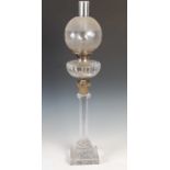 A late 19th/ early 20th century brass mounted glass Corinthian column oil lamp, the clear and