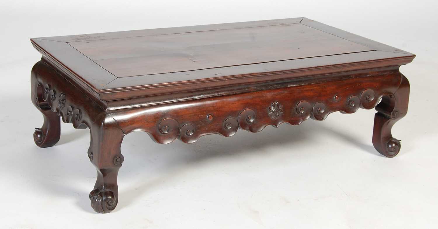 A Chinese dark wood kang table, late 19th/ early 20th century, the panelled rectangular top above