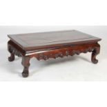 A Chinese dark wood kang table, late 19th/ early 20th century, the panelled rectangular top above
