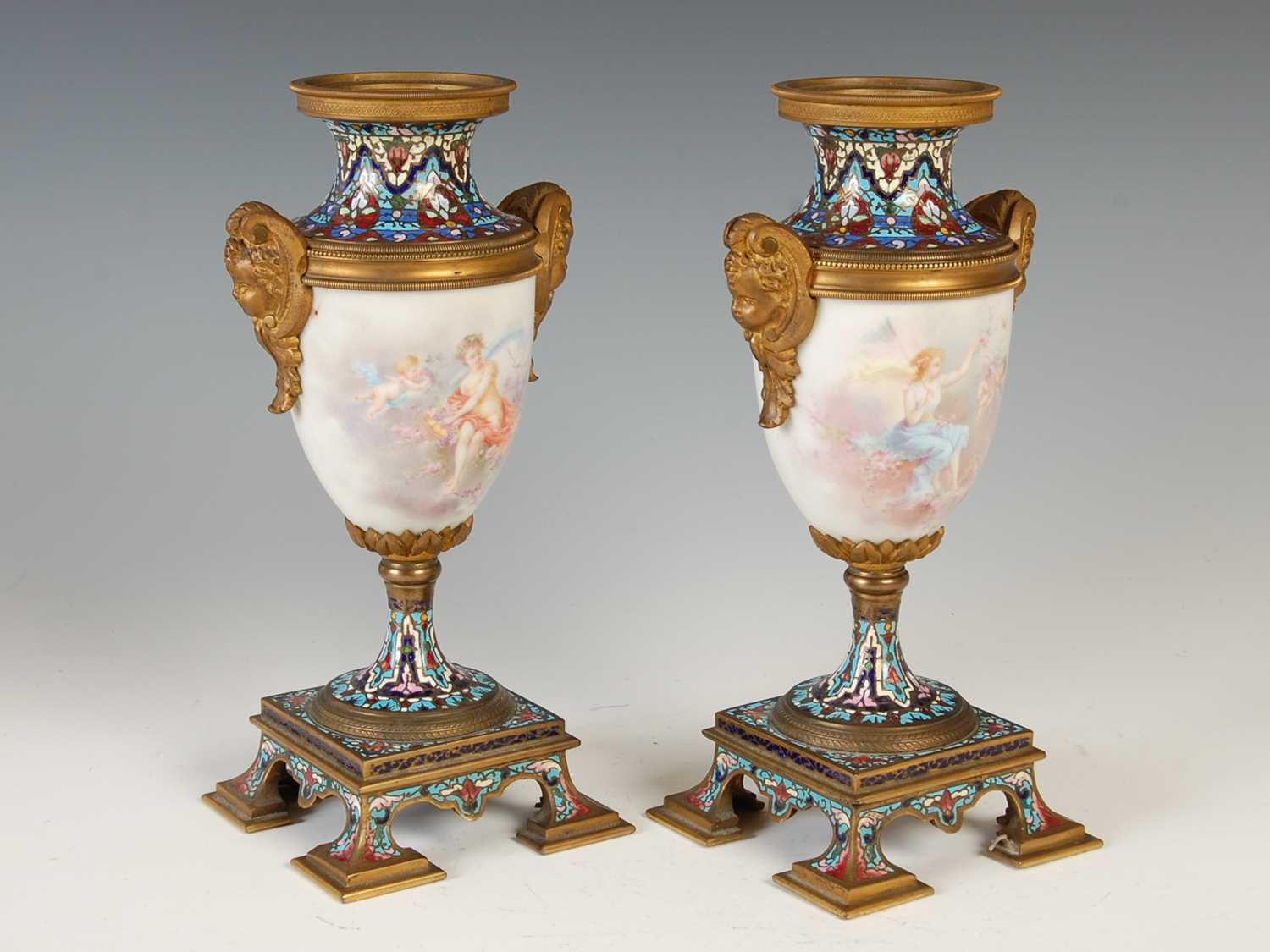 A pair of gilt metal mounted hand-painted porcelain urns, decorated with classical maidens and