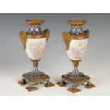 A pair of gilt metal mounted hand-painted porcelain urns, decorated with classical maidens and