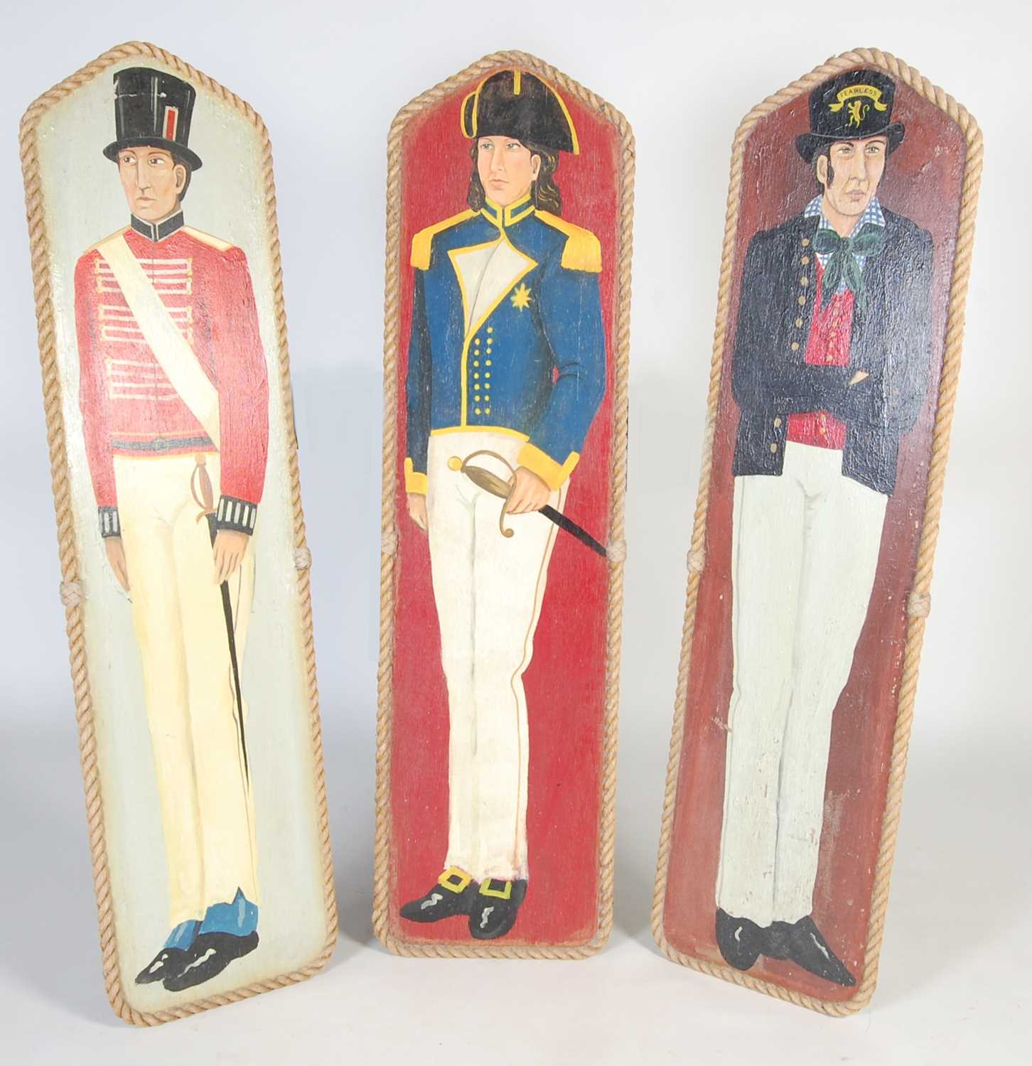 Three vintage hand painted fairground boards, decorated with military figures within rope mounted