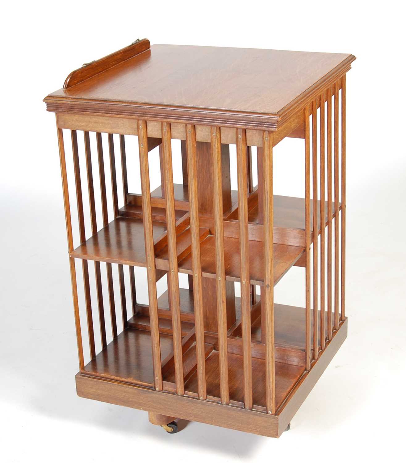 A late 19th/ early 20th century oak revolving bookcase, the square hinged top opening to a book rest