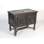 An antique stained oak coffer on integral stand, the hinged cover with two incised figural carved