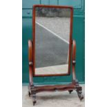 A Victorian mahogany cheval mirror, the hinged rectangular mirror plate on scroll carved supports