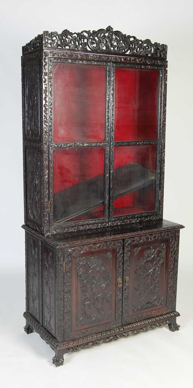 A Chinese dark wood display cabinet/ bookcase, late 19th/ early 20th century, the upper section with
