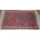 A madder ground Kilim rug decorated with two hexagonal-shaped medallions worked in puce, orange,