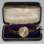 A 9ct gold cased ladies wristwatch with engine-turned Arabic numeral dial and yellow metal