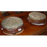 A pair of mahogany upholstered circular footstools, each with four bun feet.