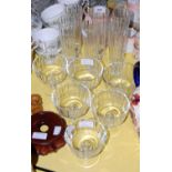 Six clear glass champagne flutes together with six similar pedestal sundae dishes.
