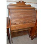 An early 20th century oak roll-top desk with shaped gallery back, the roll-top opening to a desk