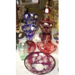 A collection of coloured overlaid glassware to include a purple and clear glass table lamp and small