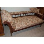 A 19th century dark wood chaise longue with floral upholstery.