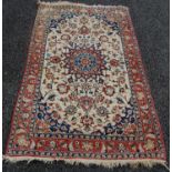 An Indian rug, 20th century, the rectangular beige coloured field centred with a blue and madder