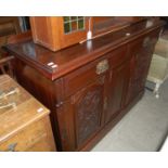 An Art Nouveau mahogany sideboard with two long drawers above two cupboard doors, each with carved