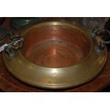 A brass and copper twin handled warming dish / bowl, the brass with lined detail, the copper with