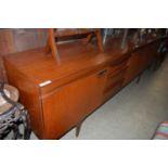 A mid 20th century teak dining room suite, comprising long sideboard, extending dining table and six