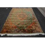 A 20th century green ground Persian style rug, centred with a peach and blue ground floral medallion