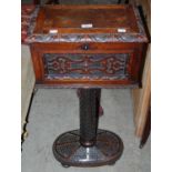 An antique carved oak tea poy on cylindrical column with scale carved detail resting on domed oval