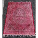 A small prayer mat, 20th century, the madder ground centred with hexagonal-shaped lozenge within a