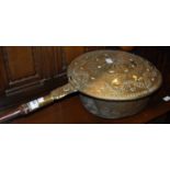 An antique brass bed warming pan with turned wooden handle
