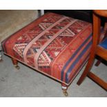 A modern Kelim style square upholstered footstool raised on turned supports with brass cups and