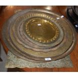 A collection of eight vintage Middle Eastern brass trays, seven circular and one rectangular