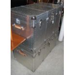 A pair of polished alloy steamer trunks