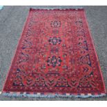A Persian rug, the madder ground centred with blue ground star-shaped foliate motifs within a