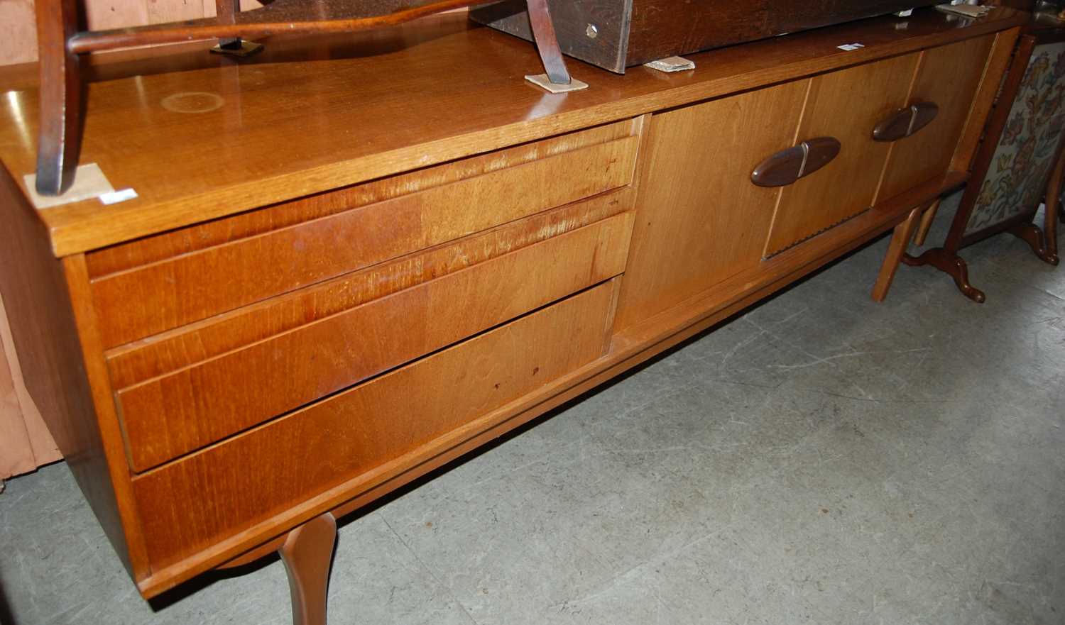 A stylish mid 20th century teak sideboard, set with a bank of three drawers, two cupboard doors