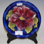 A Moorcroft blue ground dish, decorated with stylised flower, impressed and painted marks, 18.5cm