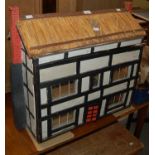 A dolls house, modelled on a Tudor mansion with thatched roof, together with a box of assorted dolls