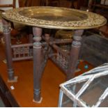 An Indian brass topped occasional table on folding base, the underside of the brass table top