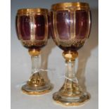 A pair of early 20th century Bohemian clear and amethyst overlaid glass goblets with richly gilded