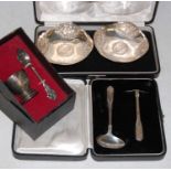 A cased Indian silver spoon and pusher set, and cased white metal egg cup and spoon, both