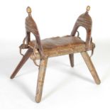 A Persian white metal mounted dark wood 'camel' type stool,