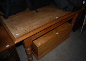 A pine dining table raised on four turned supports.