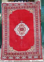 A Persian rug, 20th century, the madder ground centred with a caramel and white coloured lozenge