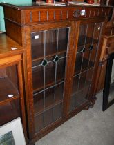 An oak Arts and Crafts style bookcase with two Astragal glazed doors opening to an interior with