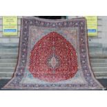 A 20th century Persian rug, centred with a dark blue and pink oval medallion on a ground of