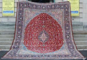 A 20th century Persian rug, centred with a dark blue and pink oval medallion on a ground of