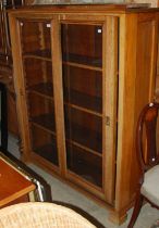 An early 20th century oak bookcase with two glazed sliding doors with three adjustable shelves,